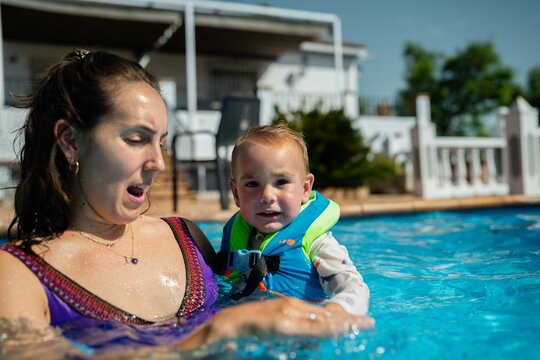 Mother and toddler enjoying summer vacation in swimming pool
