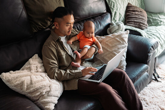 Asian father working remotely with baby at home