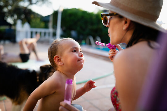 Mother blowing bubbles for happy toddler son