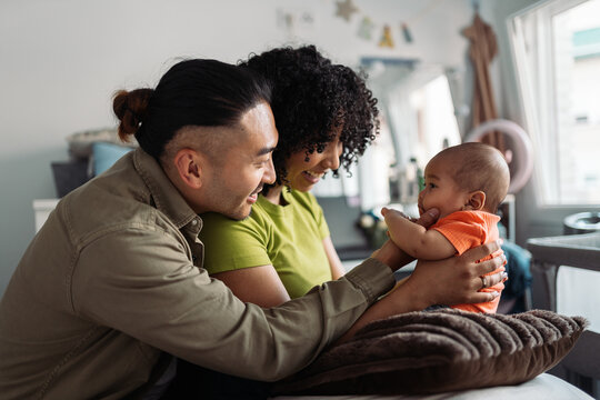 Diverse family parents playing with baby at home