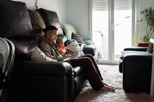 Asian father working remotely with baby at home