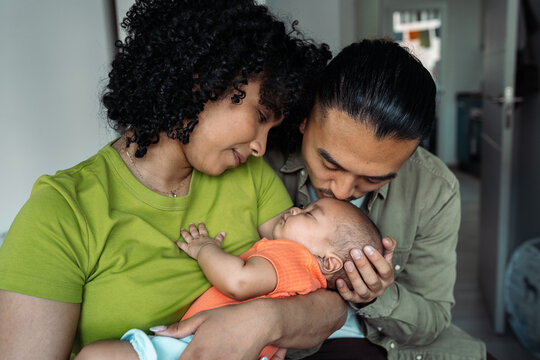 Diverse parents bonding with newborn baby at home