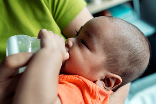 Parent bottle feeding infant baby at home
