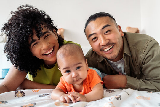 Diverse parents and baby smiling together at home