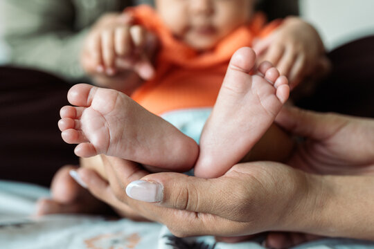 Parents' hands holding diverse newborn baby feet at home