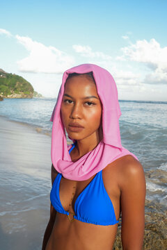 Fashion portrait of woman wearing a pink headscarf on the beach