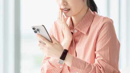 スマートフォンを見て驚く女性・ビジネスウーマン, Surprised Businesswoman Looking at a Smartphone © Trickster*