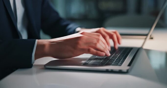 Corporate worker typing on a laptop in a dark office at night time