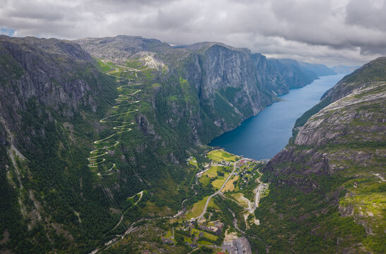 Aerial view of the winding Lysevegen road with hairpin turns descending into Lysebotn at the end of the Lysefjord, surrounded by steep mountains in Lysebotn, Rogaland, Norway.