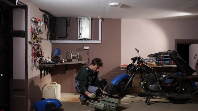 Mechanic working on a vintage motorcycle, meticulously opening a toolbox on the floor while restoring the bike in a well equipped garage with various tools on a workbench