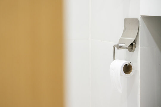 White toilet bowl and tissue paper roll in the bathroom at home.Ceramic wc bowl and roll of toilet in bathroom with modern interior.Modern toilet concept.