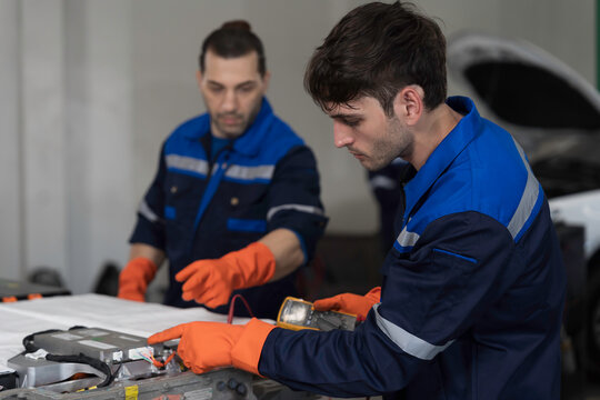 EV car repair service. Team of mechanic inspecting electric motor and inverter diagnostics, check, battery concern or repair