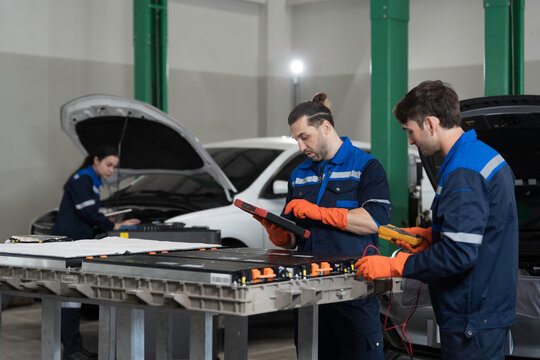 EV car repair service. Team of mechanic inspecting electric motor and inverter diagnostics, check, battery concern or repair