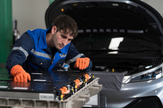 EV car maintenance garages. Technician diagnosing electric car vehicles battery, high-voltage battery service and general electric vehicle care at auto workshop