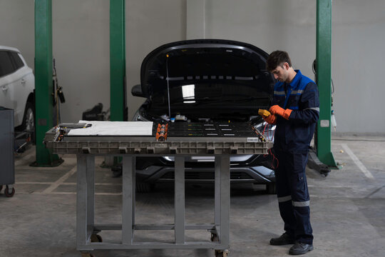 EV car maintenance garages. Technician diagnosing electric car vehicles battery, high-voltage battery service and general electric vehicle care at auto workshop