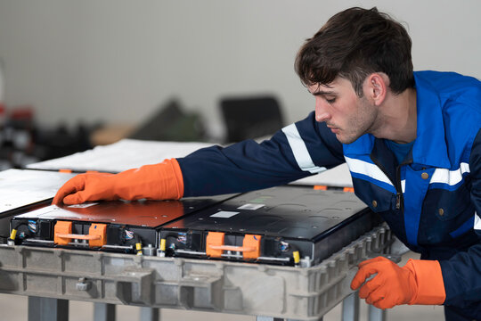 EV car maintenance garages. Technician diagnosing electric car vehicles battery, high-voltage battery service and general electric vehicle care at auto workshop