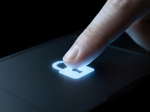 Macro close-up of a fingertip pressing a laptop trackpad with a glowing blue padlock icon, cybersecurity and biometric authentication concept, dark minimal background
