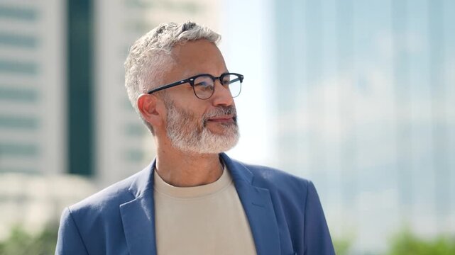 smiling mature Brazilian businessman with glasses looking forward optimistically in modern urban cit