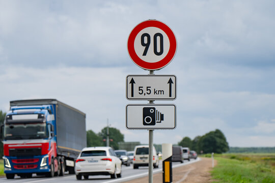 Circular speed limit 90 sign paired with distance plate and speed camera surveillance symbol regulating highway traffic flow