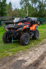 Orange all-terrain vehicle ATV quad bike equipped with off-road bull bar, winch, and cargo box parked outdoors representing utility vehicle assets © K