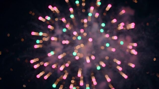 Slow motion close up of fireworks exploding into colorful bokeh and sparks, camera tracking slight pan across night sky during outdoor celebration festival, festive evening mood