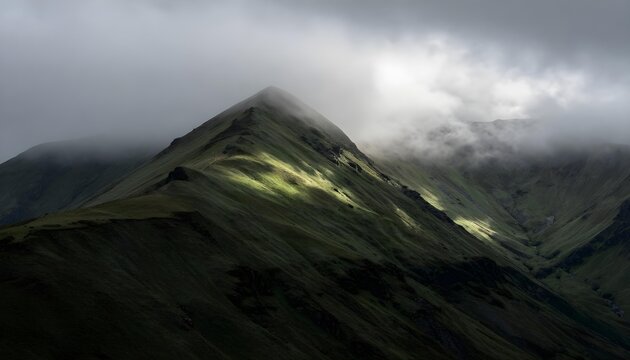 Dramatic mountain ridge bathed in sunlight piercing through moody clouds