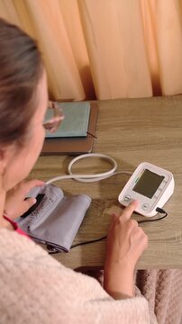 Measuring blood pressure at home with a digital monitor in a cozy room