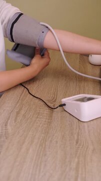 Monitoring blood pressure at home with a digital device on a wooden table