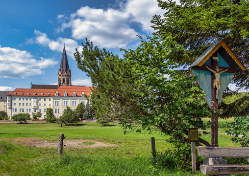 Wegkreuz und Bank dahinter die Erzabtei Sankt Ottilien, Kloster der Missionsbenediktiner, Eresing, Bayern, Deuschland