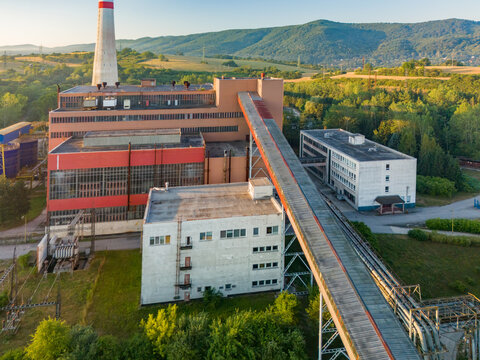 Aerial view of Zvolenska teplarenska, Inc. industrial facility with a tall chimney, red and white buildings, and a conveyor belt in Zvolen, Banskobystricky kraj, Slovakia.