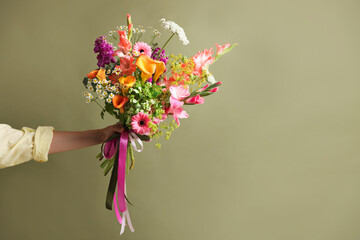 Obraz premium Woman with bouquet of beautiful vibrant flowers on olive background, closeup. Space for text