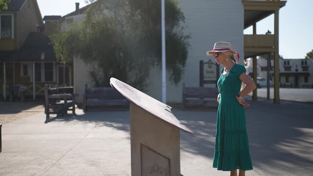 Mature woman walks in Casa Grande while reading about history on a morning in Sonoma, California just after the sunrise.