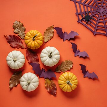 Flat lay composition of decorative pumpkins autumn leaves and halloween bats on orange background