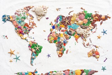 Fototapeta premium World map made of colorful sea shells starfish and glass on white sand