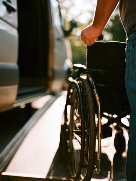 Wheelchair ramp van hand caregiver accessibility transport mobility disabled assistance outdoor vehicle wheel push support safety medical patient adult profile closeup sunlight backlight shadow