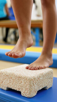 Bare foot sensory room balance exercise tactile stepping stone close up low angle therapy child standing stepping