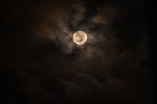 The July Full Moon is known as the ''Buck Moon'' in Native American tradition, coinciding with Guru Purnima. See black storm clouds, tree branches, electric wire, and construction,  lunar corona  