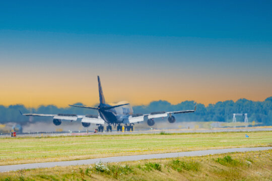 Rear view of a passenger airplane landing on runway with visible engine heat haze and summer atmosphere at the airport