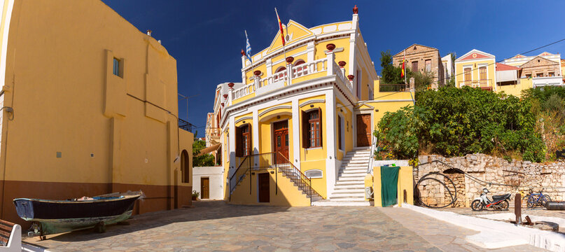 Historic neoclassical building with stone steps and colorful architecture on the waterfront of Symi Island, Dodecanese, Greece.