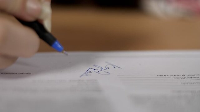 Indian female's hand signing an important official document with a blue pen. Closeup shot of businesswoman's hands putting a signature on papers - sign-on important agreement