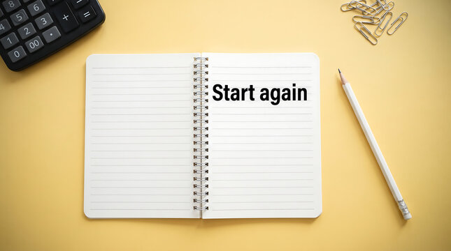 Start again concept, an open notebook with inscription start again, pencil, paper clips, calculator on yellow background for motivation or new beginnings.