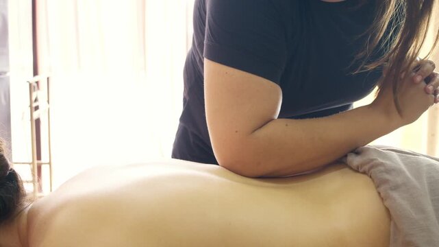 Therapist applies forearm massage across back with deep pressure. Deep tissue technique releases muscle tension and improves mobility.