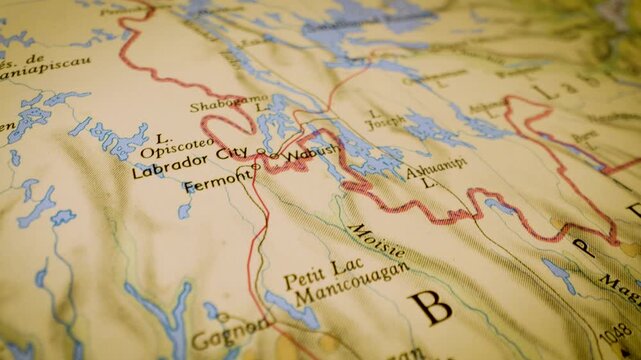 Gliding macro view over physical atlas map leading to Smallwood Reservoir, Canada