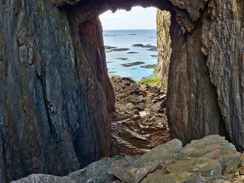 Natural rock arch frames a view of the Norwegian island archipelago from a mountain path