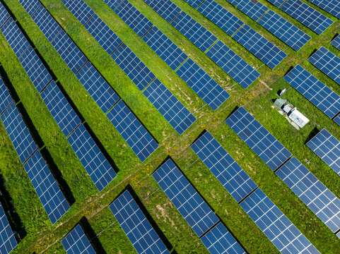Aerial view of solar photovoltaic power plant with diagonal rows of panels arranged in a field of green grass in Sudbury, Massachusetts, USA.