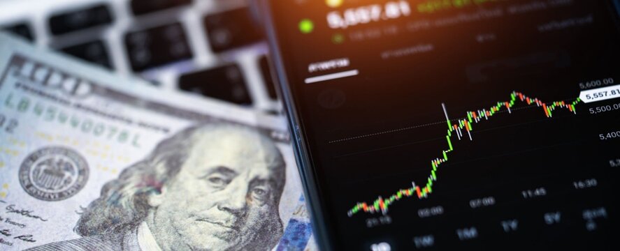 Digital chart rises beside dollar bills and keyboard. Viewer sees growth and financial data in focus. No people shown, no emotion to convey. Use for finance, investment, or tech business concepts