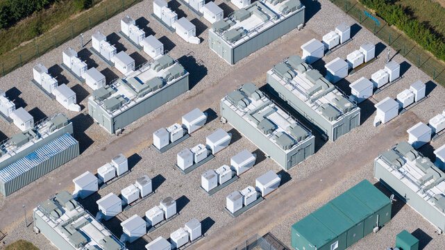 Aerial view of Pelham Storage Limited, a battery energy storage facility featuring rows of white containers and green utility units on a gravel site in Bishop's Stortford, England, United Kingdom.