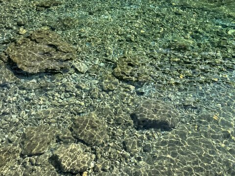 Rocky seabed pebbles stones transparent water.