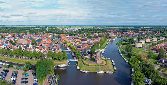 Aerial view of the historic town of Dokkum featuring a traditional windmill, canal, bridges, and charming rooftops in Dokkum, Friesland, Netherlands.