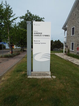 Gatineau, Quebec, Canada &ndash; June 9, 2026: A modern directional sign displays the building name "&Eacute;difice Auberge Charles-Symmes" and "Mus&eacute;e de l'Auberge Symmes" at 1 Rue Front.